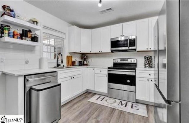 kitchen featuring stainless steel appliances, white cabinets, sink, and light wood-type flooring