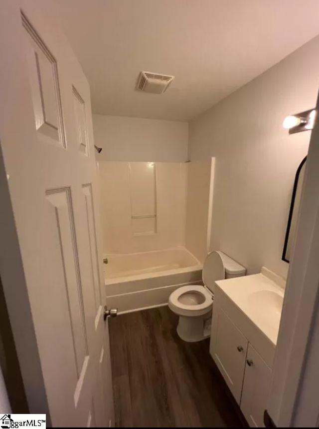 full bathroom with toilet, shower / bathing tub combination, wood-type flooring, and vanity