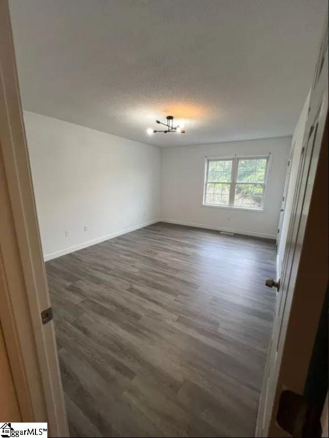 spare room featuring a textured ceiling and dark wood-type flooring