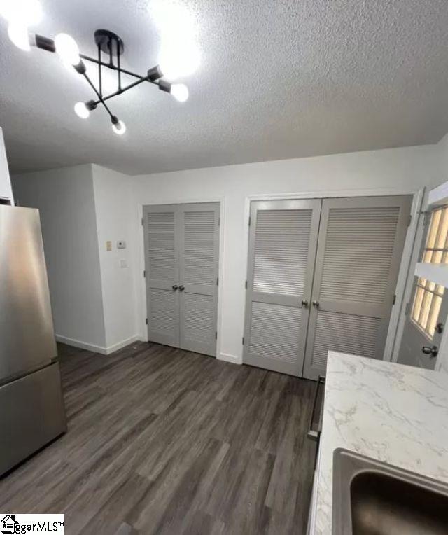 kitchen with sink, a textured ceiling, an inviting chandelier, stainless steel fridge, and dark hardwood / wood-style flooring