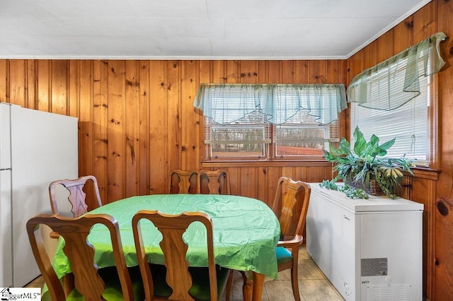 dining space featuring ornamental molding, wooden walls, and light tile patterned flooring