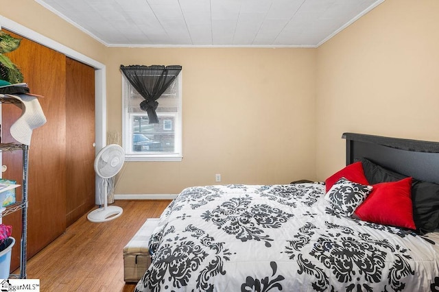 bedroom with a closet, light wood-type flooring, and ornamental molding