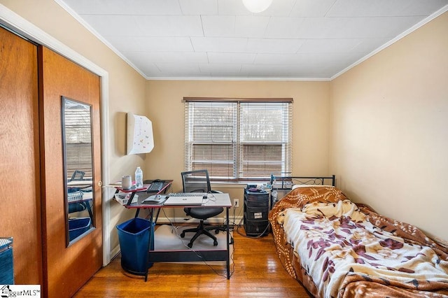 bedroom with a closet, ornamental molding, and hardwood / wood-style flooring