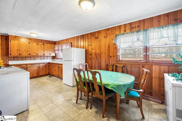 kitchen with washer / dryer, wooden walls, and white fridge