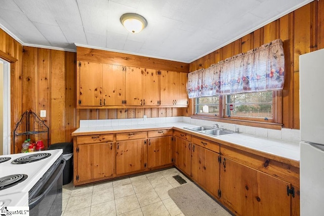 kitchen with white appliances, tile countertops, wood walls, and sink