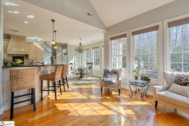 kitchen featuring an inviting chandelier, a breakfast bar area, decorative backsplash, cream cabinets, and decorative light fixtures