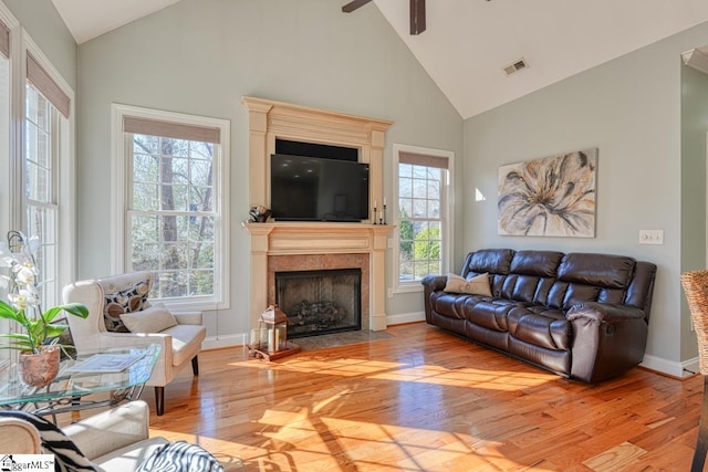 living room featuring a fireplace, ceiling fan, light hardwood / wood-style floors, and a wealth of natural light