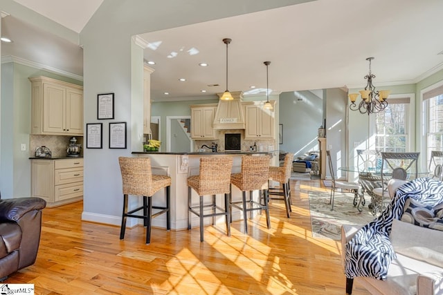 kitchen featuring decorative light fixtures, cream cabinetry, tasteful backsplash, kitchen peninsula, and a notable chandelier