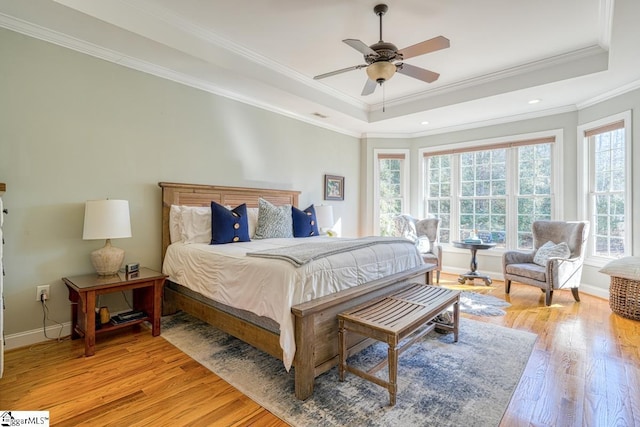 bedroom featuring ceiling fan, crown molding, multiple windows, and a tray ceiling