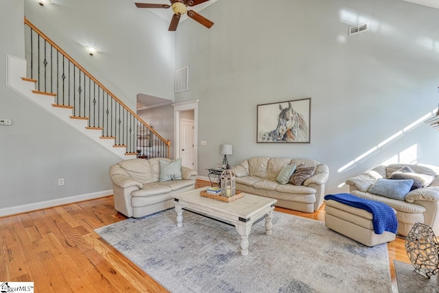 living room with ceiling fan, light hardwood / wood-style floors, and a high ceiling