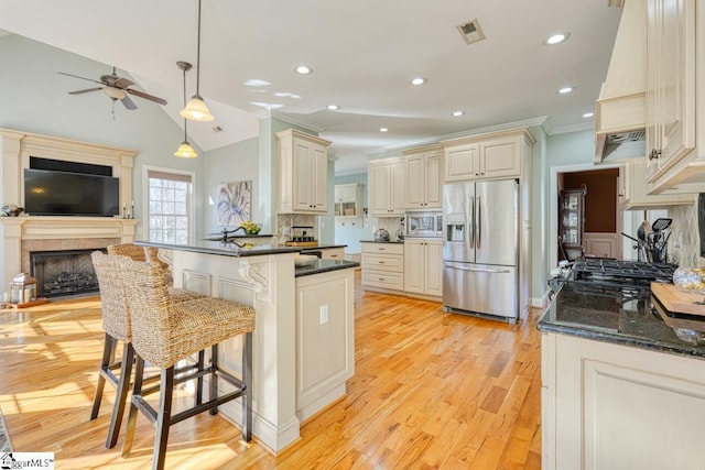 kitchen featuring decorative light fixtures, ceiling fan, tasteful backsplash, a breakfast bar area, and appliances with stainless steel finishes