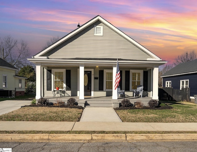 view of front of home with covered porch and a lawn