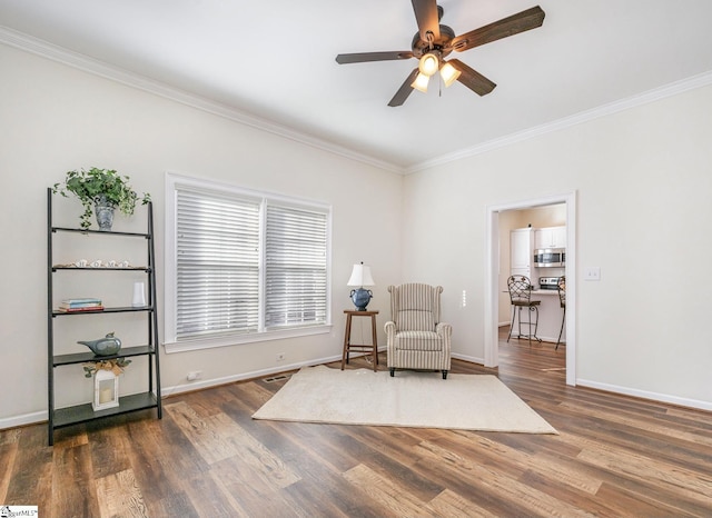 sitting room with ceiling fan, crown molding, and dark hardwood / wood-style flooring