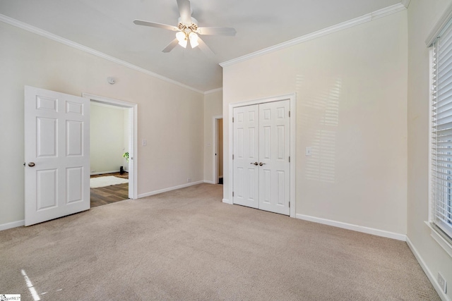 unfurnished bedroom with ceiling fan, light colored carpet, ornamental molding, and a closet