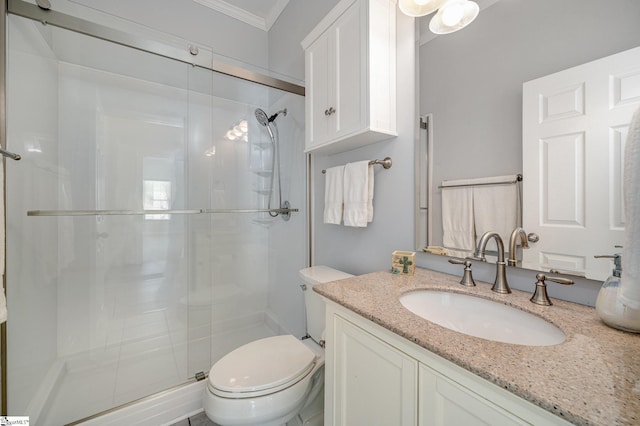 bathroom featuring toilet, vanity, a shower with shower door, and crown molding