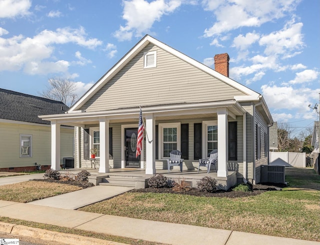 bungalow-style home with a front yard, a porch, and central air condition unit