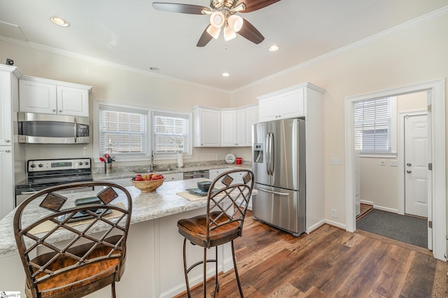 kitchen with stainless steel appliances, dark wood-type flooring, light stone counters, sink, and white cabinetry