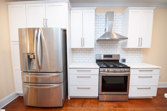 kitchen with dark wood-type flooring, stainless steel appliances, wall chimney range hood, tasteful backsplash, and white cabinetry