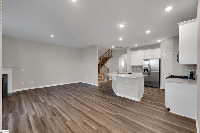 kitchen featuring stainless steel fridge with ice dispenser, white cabinetry, a center island with sink, and hardwood / wood-style flooring