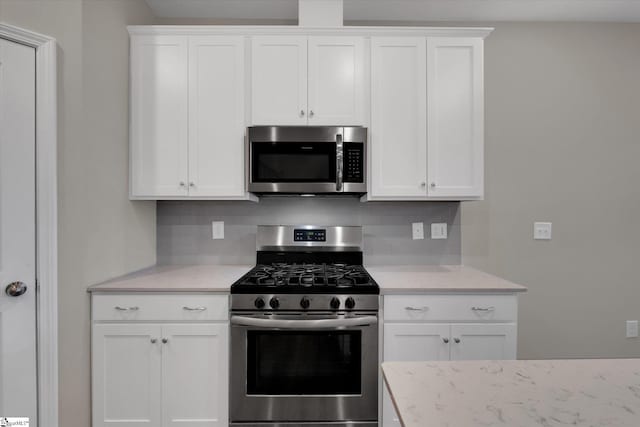 kitchen featuring white cabinets, decorative backsplash, and appliances with stainless steel finishes