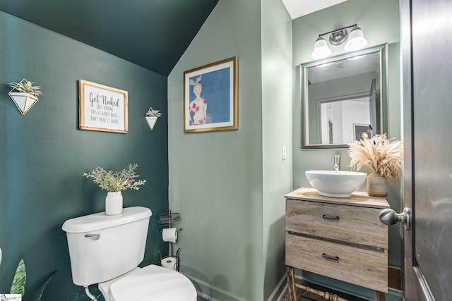 bathroom with lofted ceiling, vanity, and toilet