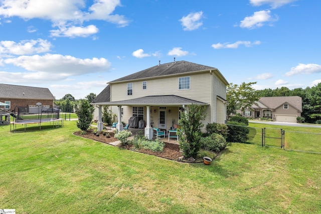 rear view of property featuring a patio area, a lawn, and a trampoline