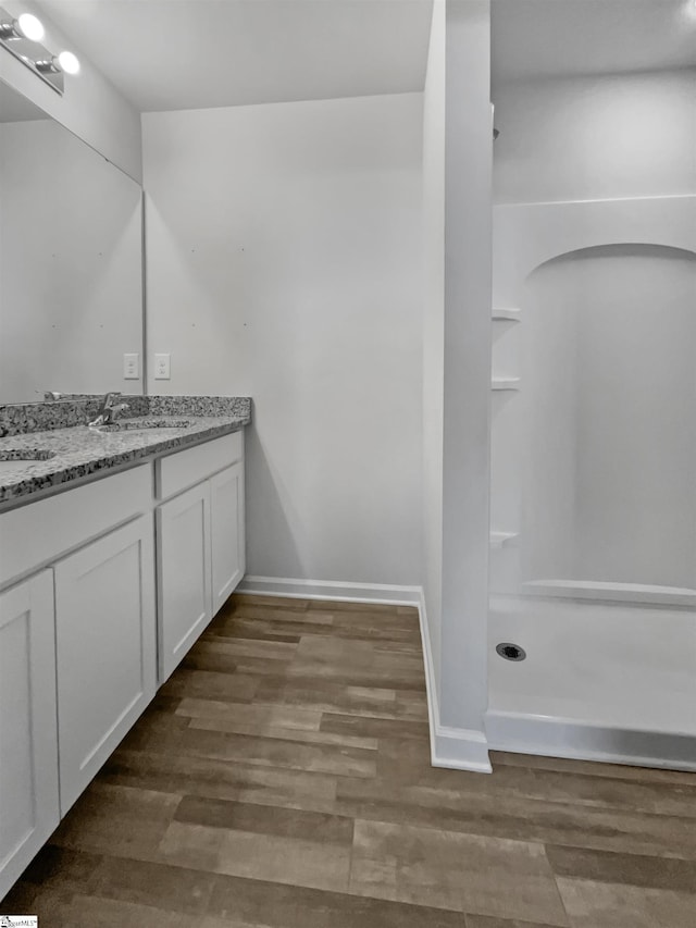 bathroom featuring walk in shower, vanity, and wood-type flooring