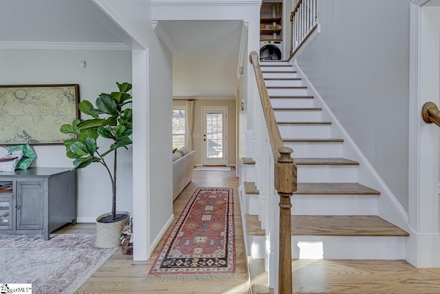 staircase featuring washer / dryer, ornamental molding, and wood-type flooring