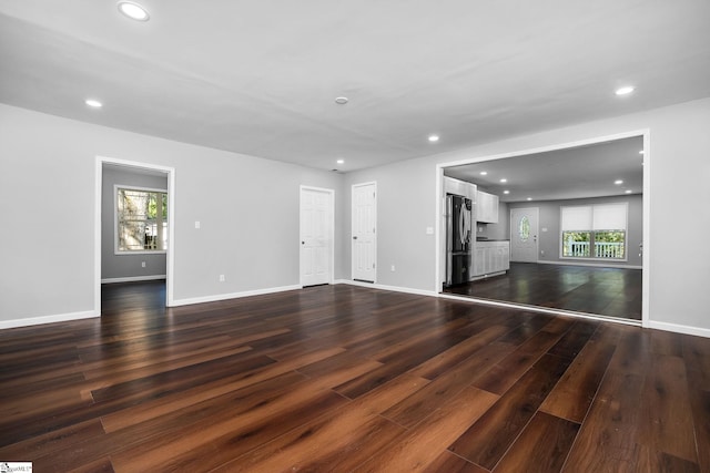 unfurnished living room with a healthy amount of sunlight and dark hardwood / wood-style floors