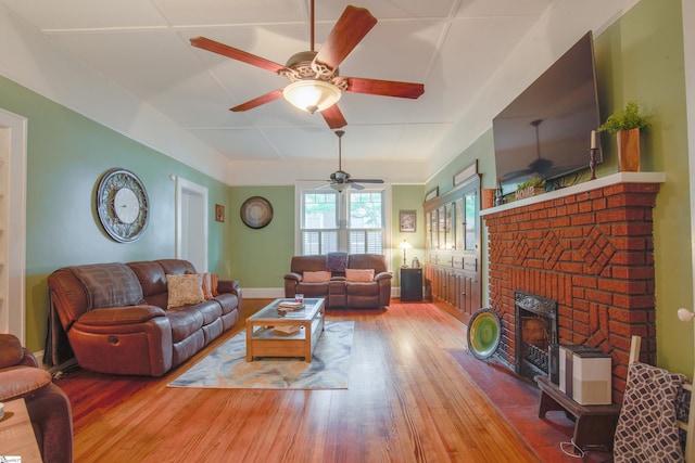 living room with a brick fireplace, hardwood / wood-style floors, and ceiling fan