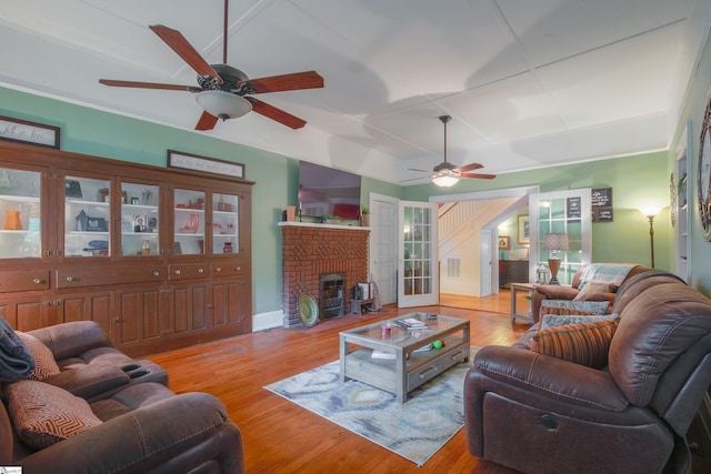 living room with a brick fireplace, ceiling fan, and light hardwood / wood-style flooring