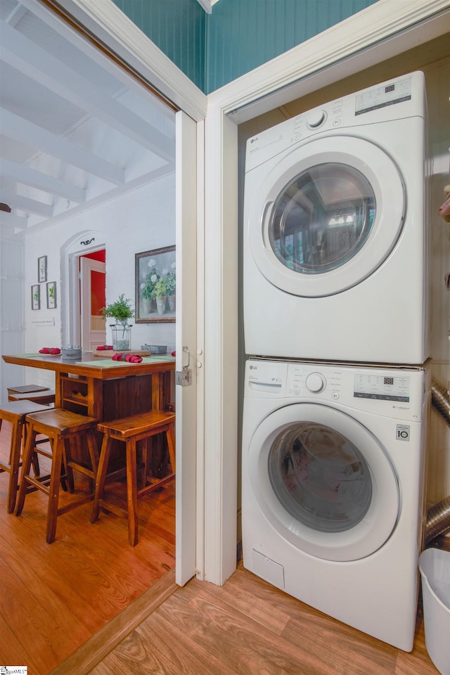 washroom with stacked washer and clothes dryer and light wood-type flooring