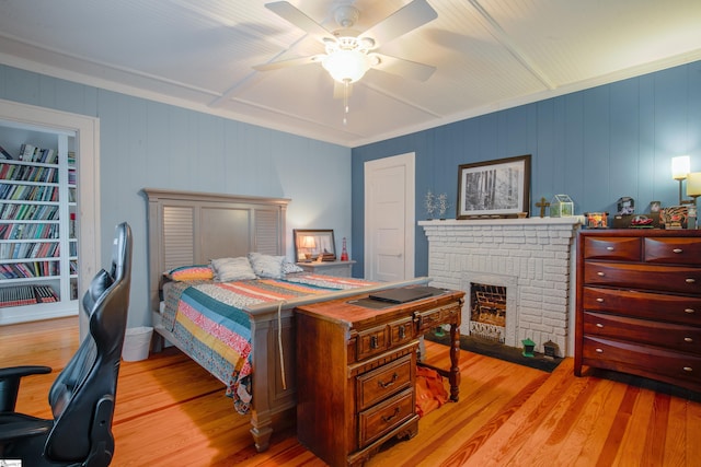 bedroom with a fireplace, ceiling fan, and light hardwood / wood-style flooring