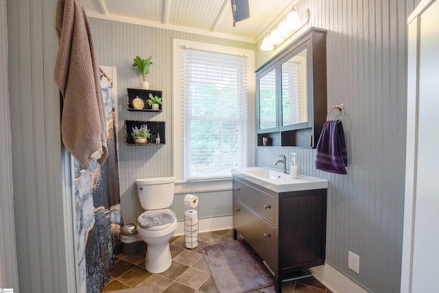 bathroom featuring tile patterned flooring, wood walls, toilet, vanity, and ornamental molding