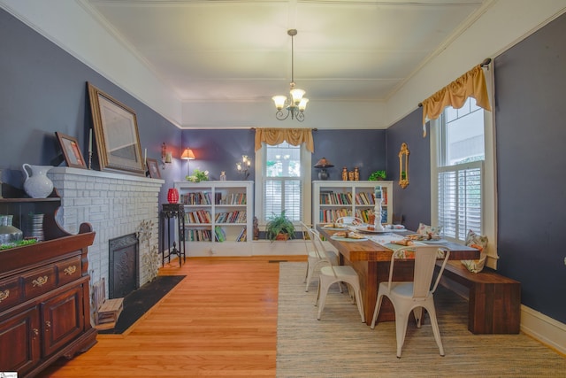 dining area featuring a fireplace, a notable chandelier, and light hardwood / wood-style floors