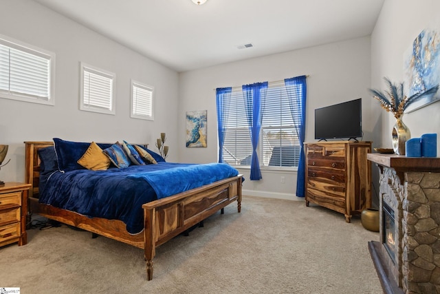 bedroom featuring light carpet and a fireplace