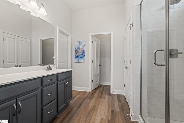 bathroom with hardwood / wood-style flooring, a shower with shower door, and vanity