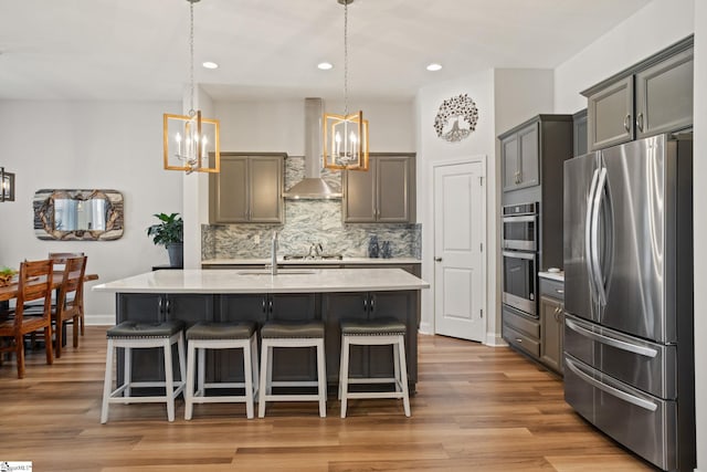 kitchen featuring appliances with stainless steel finishes, hanging light fixtures, a breakfast bar, extractor fan, and tasteful backsplash