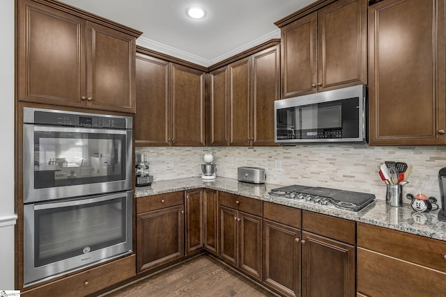 kitchen with stainless steel appliances, dark hardwood / wood-style floors, decorative backsplash, and light stone countertops