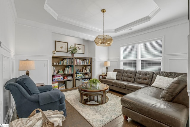 living room featuring a raised ceiling, ornamental molding, and dark wood-type flooring