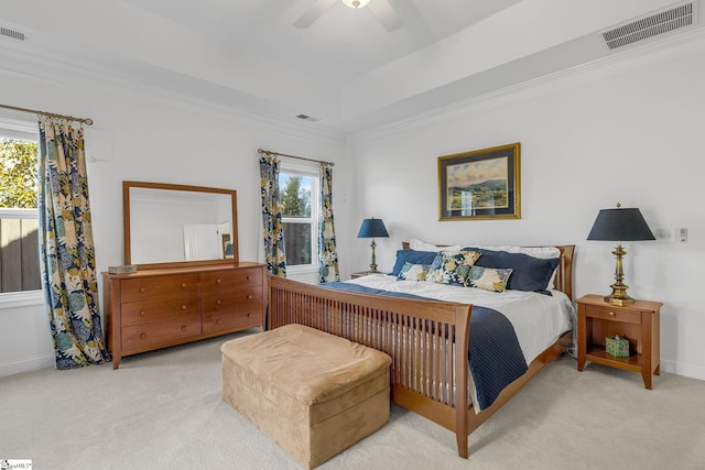 bedroom with ceiling fan, light colored carpet, ornamental molding, and a tray ceiling