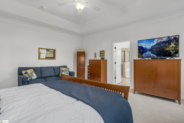 carpeted bedroom featuring ceiling fan, a raised ceiling, ensuite bathroom, and crown molding