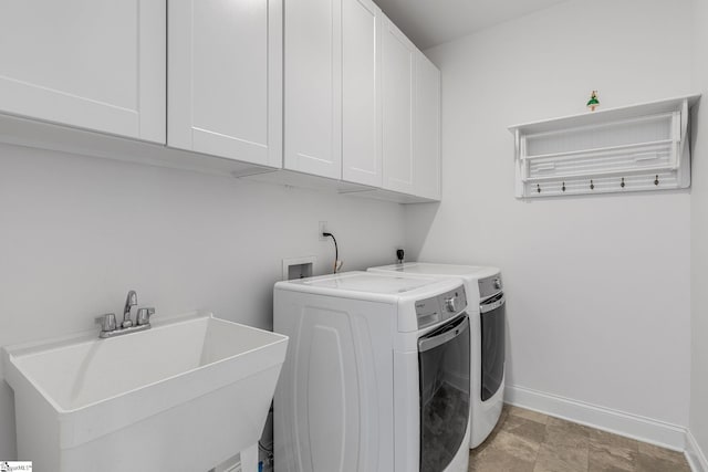 washroom with cabinets, washing machine and clothes dryer, and sink