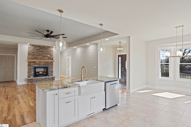 kitchen featuring light stone counters, dishwasher, decorative light fixtures, white cabinetry, and sink