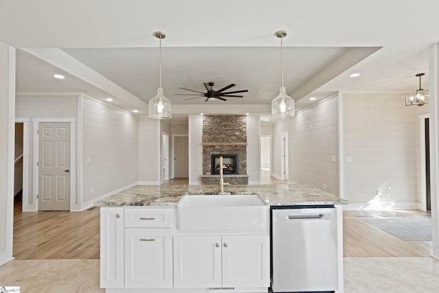 kitchen featuring sink, decorative light fixtures, white cabinetry, stainless steel dishwasher, and light stone countertops