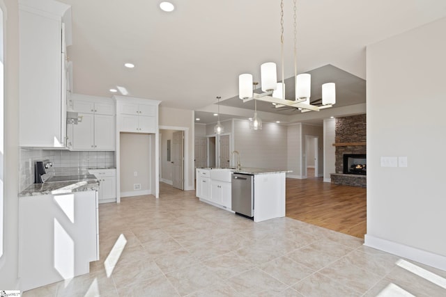 kitchen featuring hanging light fixtures, white cabinetry, stainless steel dishwasher, and a fireplace