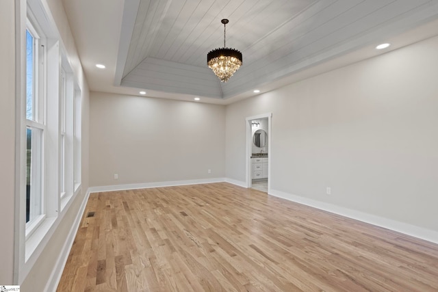 empty room with light hardwood / wood-style flooring, an inviting chandelier, wooden ceiling, and a tray ceiling