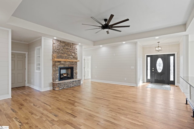 unfurnished living room featuring ceiling fan with notable chandelier, light wood-type flooring, and a fireplace