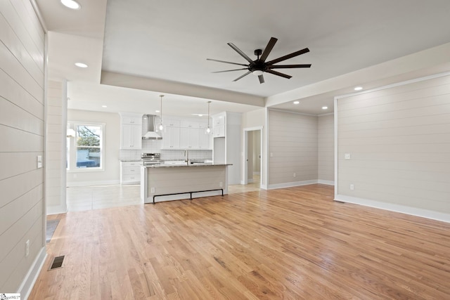 unfurnished living room with sink, ceiling fan, and light hardwood / wood-style floors