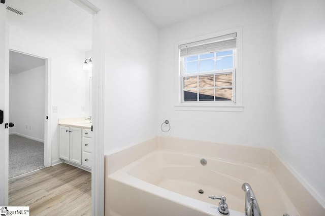 bathroom featuring hardwood / wood-style floors, a bath, and vanity